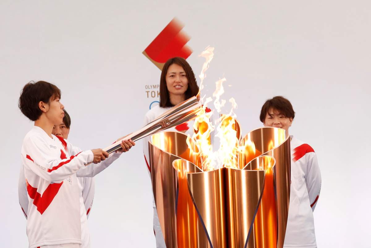 The torch is lit by a member of Japan's women's national soccer team "Nadeshiko Japan" during the Tokyo 2020 Olympic Torch Relay Grand Start in Naraha, Fukushima prefecture, northeastern Japan, Thursday, March 25, 2021. The torch relay for the postponed Tokyo Olympics began its 121-day journey across Japan on Thursday and is headed toward the opening ceremony in Tokyo on July 23. (Kim Kyung-Hoon/Pool Photo via AP).