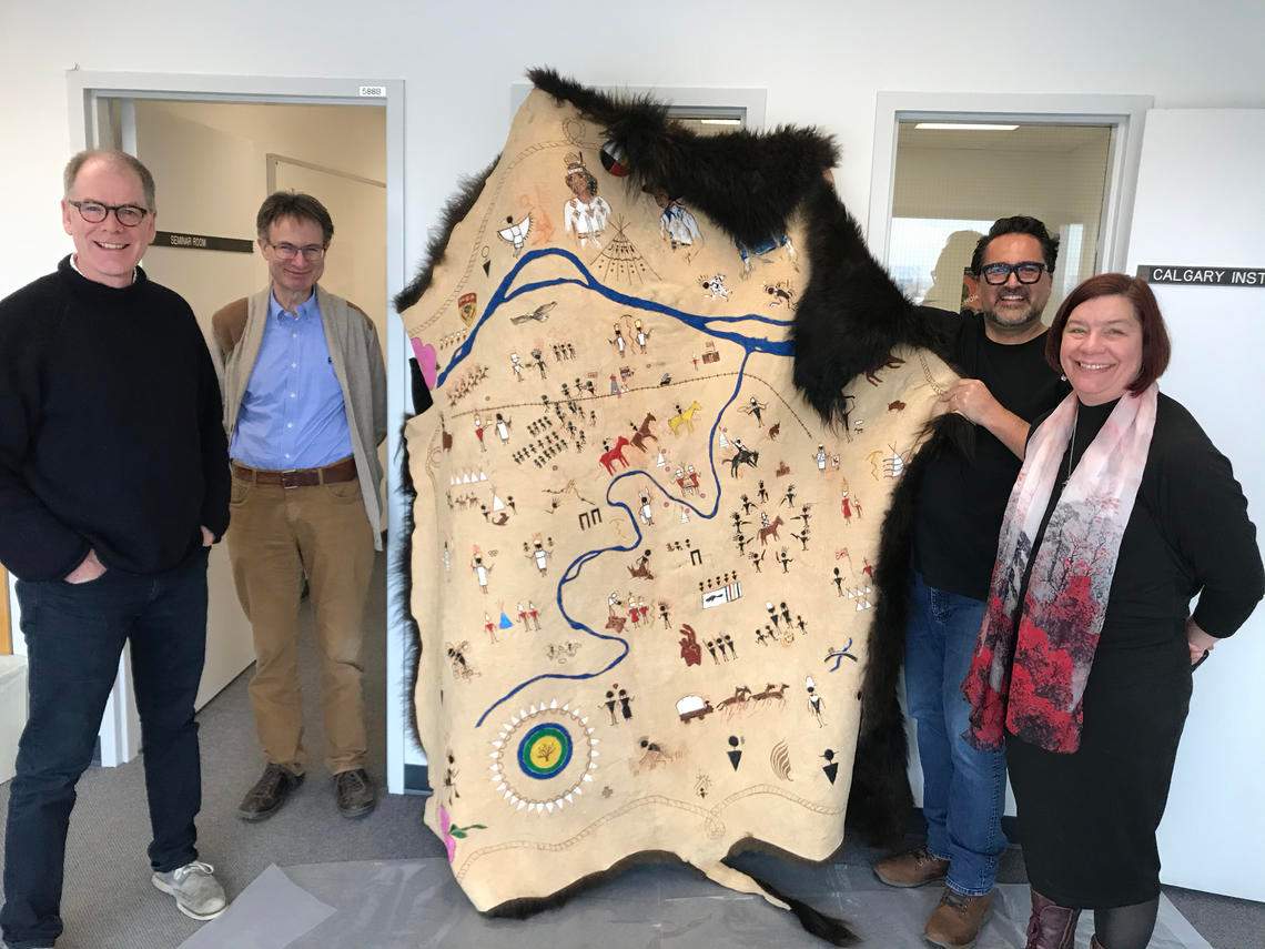 Adrian Stimson and team poses for the camera with the final version of the bison robe map.