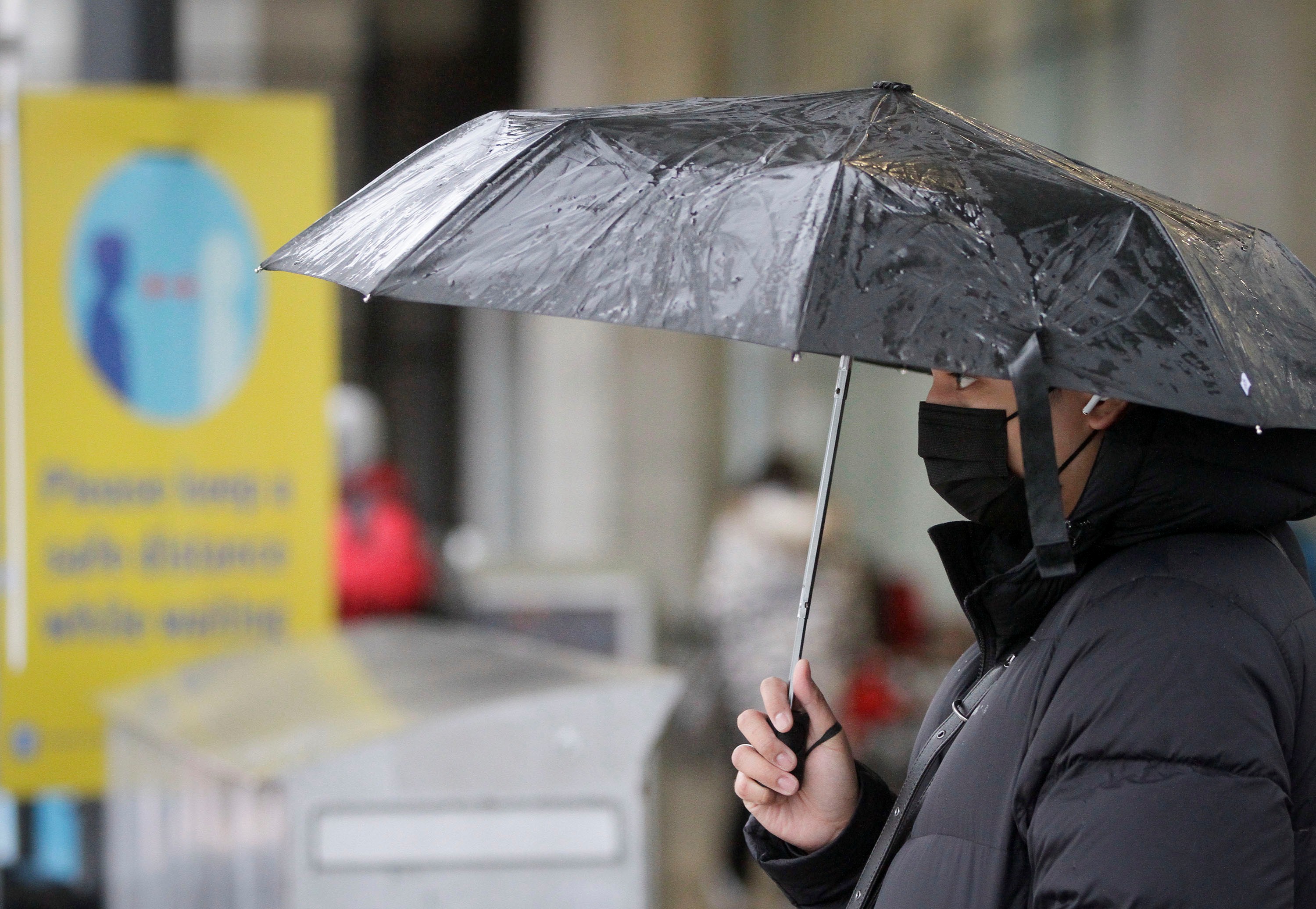 A person wearing a face mask waits to cross a street in Vancouver, British Columbia, Canada