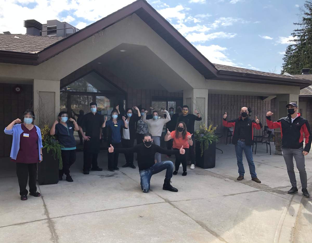 Paramount Fine Foods CEO and founder Mohamad Fakih (centre) kneels in front of staff and volunteers outside of Horizon Place in west London, Ont.