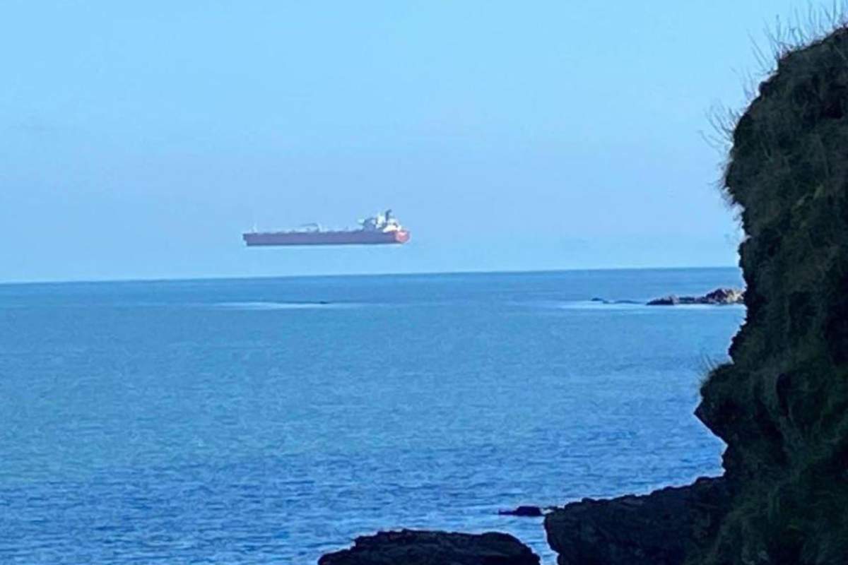 A tanker appears to hover above the water off the coast of Cornwall, England, in this photo captured by a pedestrian from shore.