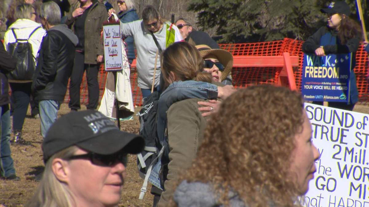 People hug at a Calgary rally protesting COVID-19 restrictions on March 20, 2021.