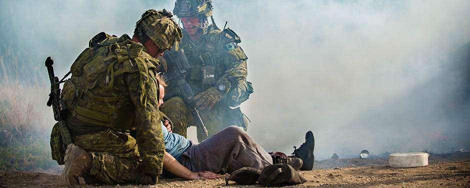Members of the Royal 22e Régiment escort a civilian with simulated injuries to a secure area for medical treatment after accident scenario during Exercise Maple Resolve at CFB Wainwright, Alta. on 15 May 2018.