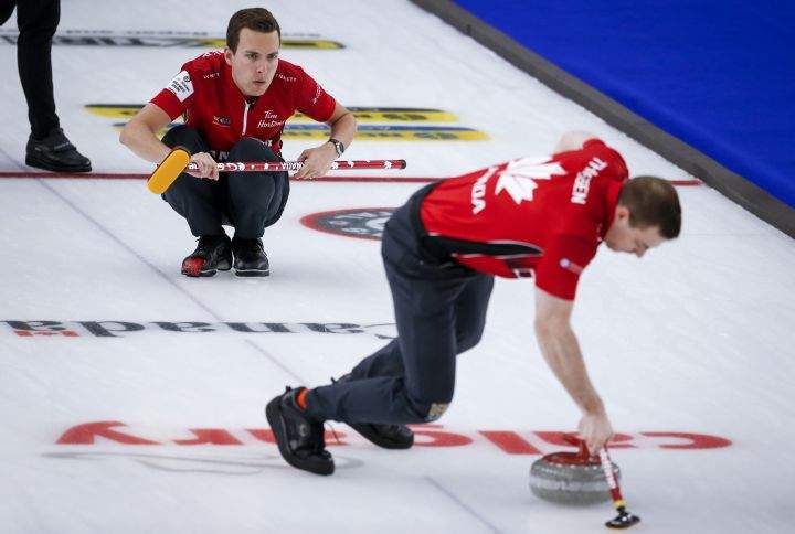 Team Canada skip Brendan Bottcher, left, makes a shot as second Brad Thiessen sweeps against Scotland in the qualification round at the Men's World Curling Championships in Calgary, Alta., Friday, April 9, 2021.