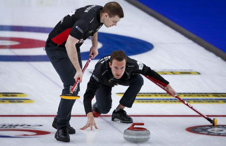 Team Canada skip Brendan Bottcher, right, makes a shot  as second Brad Thiessen sweeps against Italy at the Men's World Curling Championships in Calgary, Alta., Tuesday, April 6, 2021.