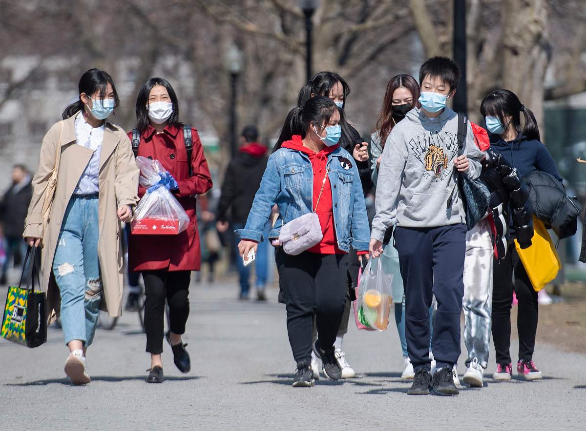 People wear face masks as they walk in a park in Montreal, Sunday, April 4, 2021, as the COVID-19 pandemic continues in Canada and around the world. 
