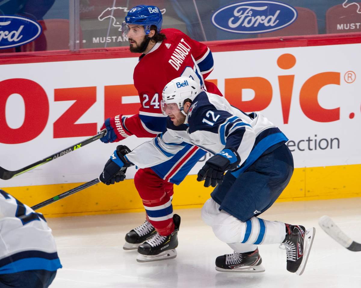 The Winnipeg Jets’ Jansen Harkins (12) checks the Montreal Canadiens’ Phillip Danault (24) during third-period NHL hockey action Thursday, April 8, 2021 in Montreal.