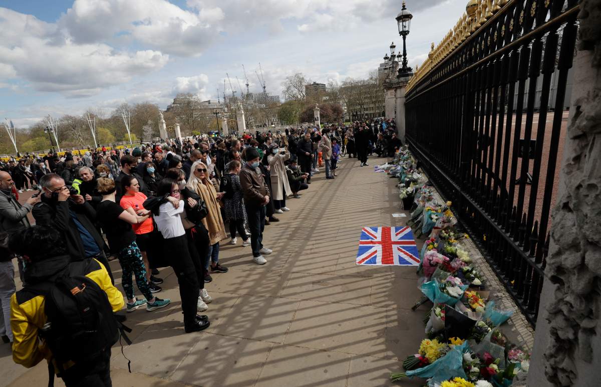 People gather to lay flowers and pay their respects to Prince Philip outside the palace gates.
