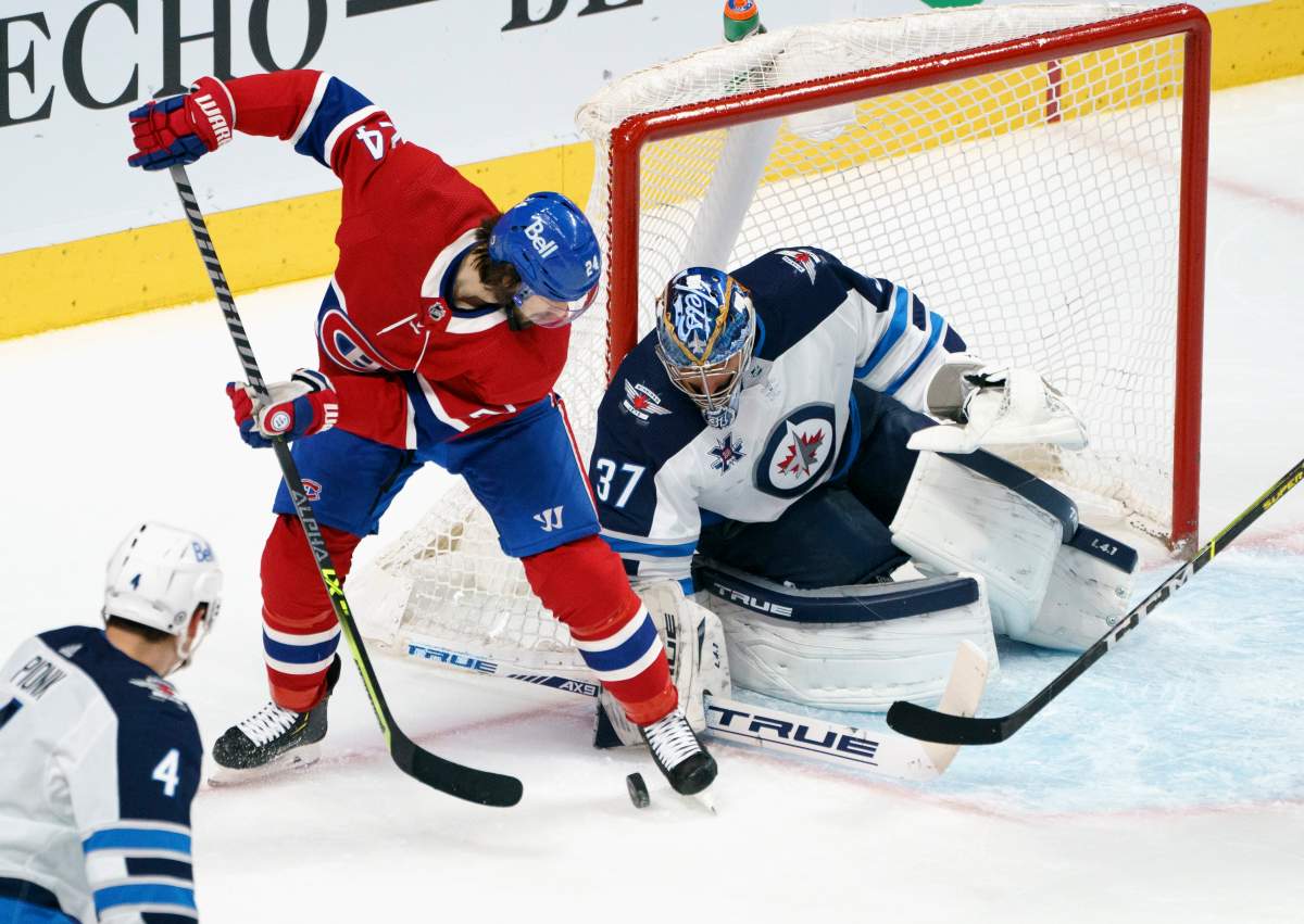 Montreal Canadiens’ Phillip Danault handles a rebound off Winnipeg Jets goaltender Connor Hellebuyck during the first period NHL hockey action in Montreal on April 30, 2021.