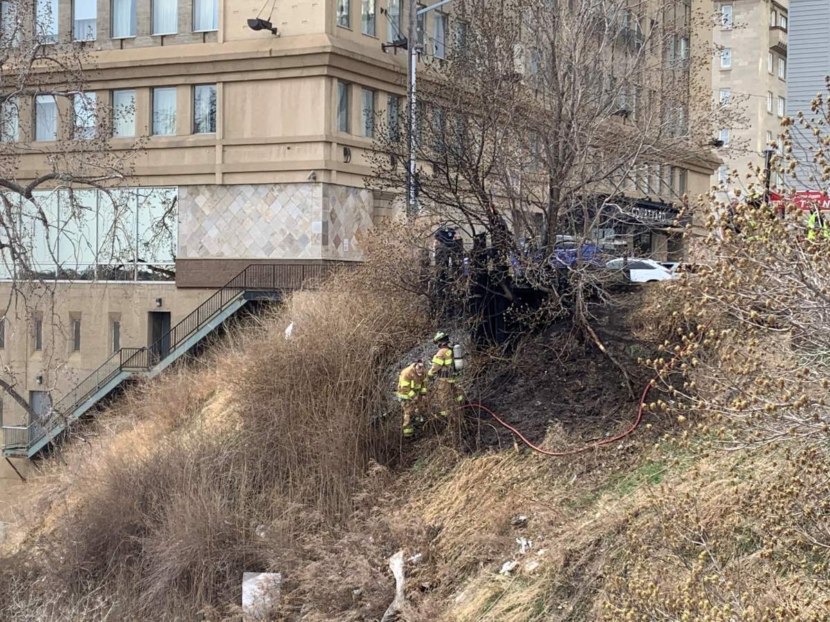 Firefighters putting out a grass fire beside the Courtyard by Marriott hotel near 99 Street and Jasper Avenue in Edmonton, Alta. on Friday, April 23, 2021.