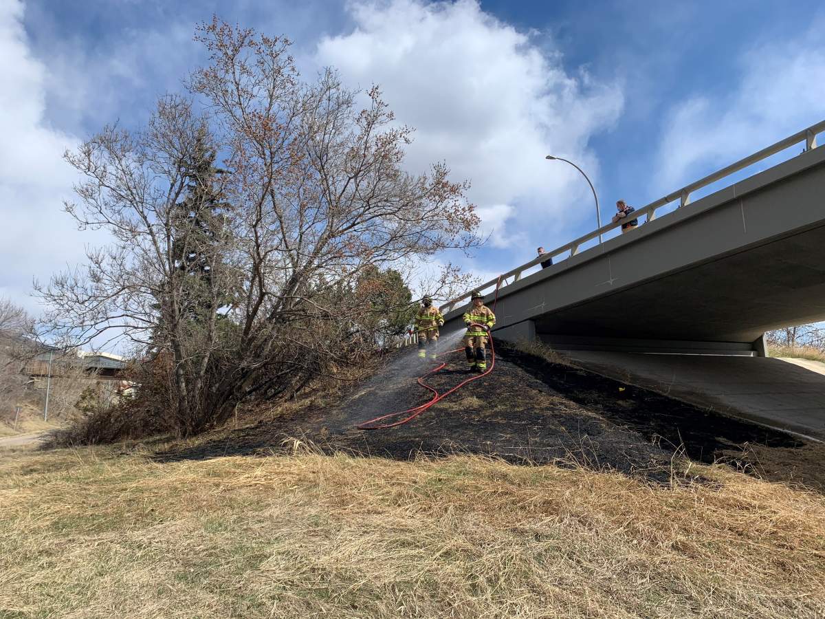 Firefighters putting out a grass fire near the Low Level Bridge in Edmonton, Alta. on Friday, April 23, 2021.