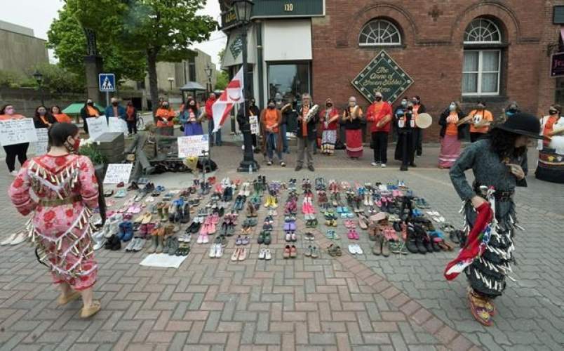 Two Indigenous dancers perform around the 215 pairs of children's shoes placed next to a Sir John A. Macdonald statue in Charlottetown on Monday, May 31, 2021, during a ceremony for the remains of 215 children found at the Kamloops Indian Residential School.