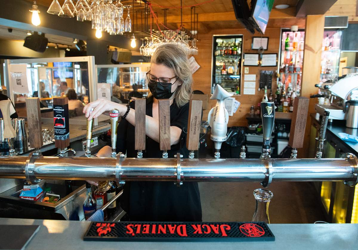A server pours a beer at a bar and restaurant in Saint-Sauveur, Que., Saturday, December 12, 2020, as the COVID-19 pandemic continues in Canada and around the world. 