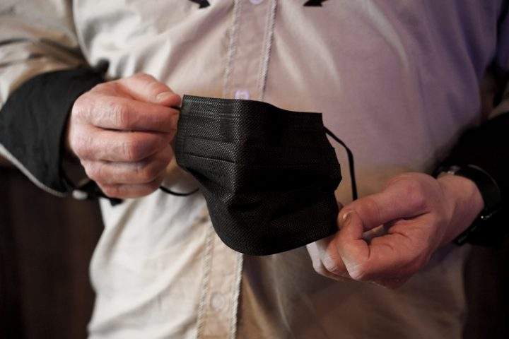 Sean Glass, a bartender at The Smiling Moose Bar/Restaurant, shows his COVID-19 protective covering he has at the ready Friday, May 14, 2021, in Pittsburgh's South Side neighborhood. 
