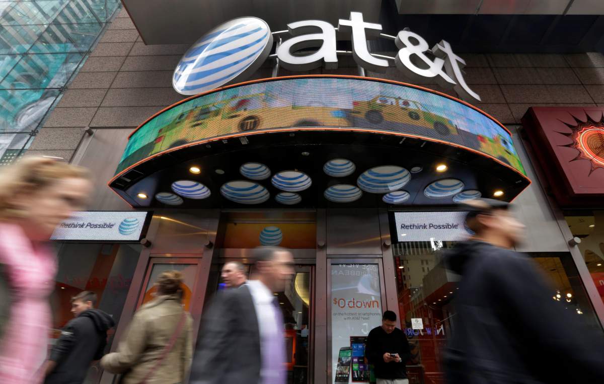 FILE - In this Oct. 21, 2014 file photo, people pass an AT&T store in New York's Times Square. AT&T will combine its media operations that include CNN HBO, TNT and TBS in a $43 billion deal with Discovery, the owner of lifestyle networks including the Food Network and HGTV.  The deal announced Monday, May 17, 2021, would create a separate media company as households increasingly abandon cable and satellite TV, looking instead at Netflix, Amazon Prime Video, Facebook, TikTok and YouTube. (AP Photo/Richard Drew, File).