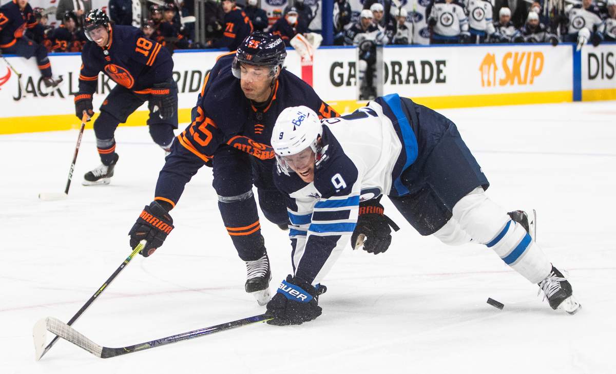 The Edmonton Oilers’ Darnell Nurse (25) and Winnipeg Jets’ Andrew Copp (9) battle for the puck during first-period NHL playoff action in Edmonton.