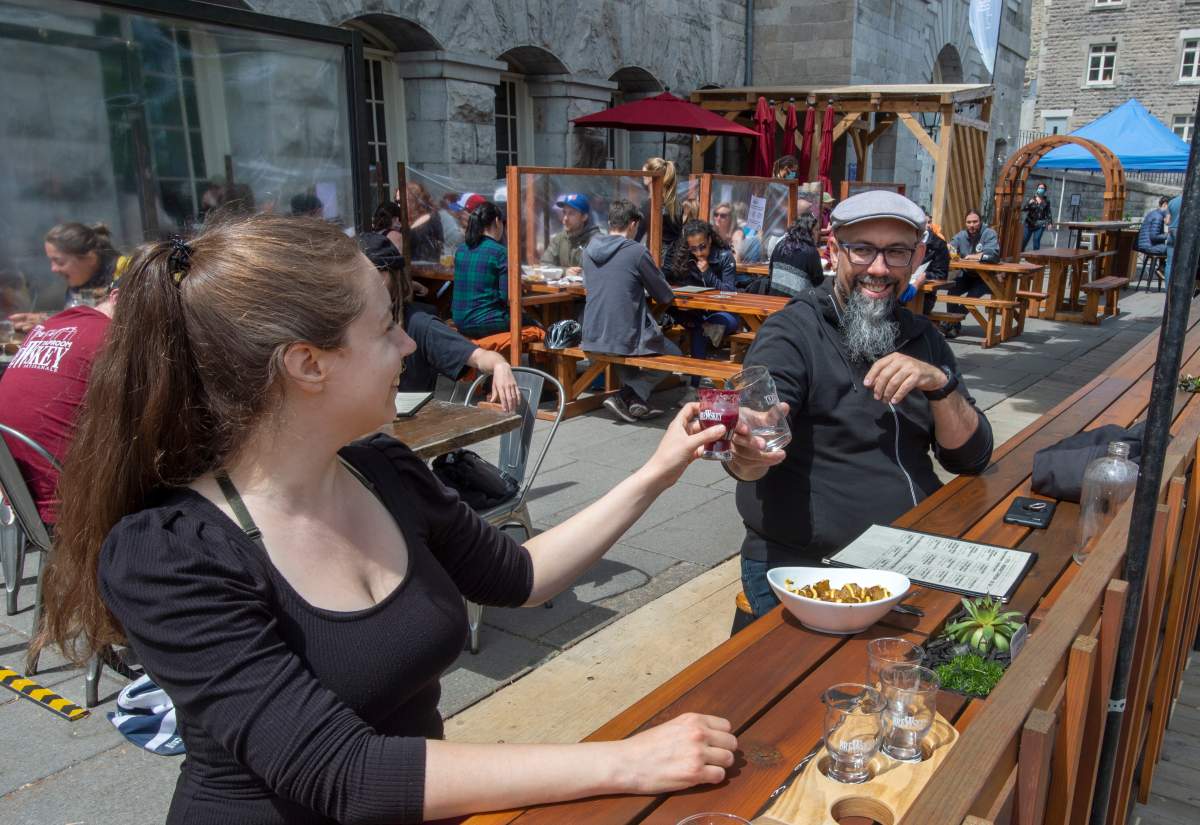 Lawrence L’Oisselle, left, and Eric Deschamps enjoy a restaurant patio as they re-open for the first time since last September in Montreal as Quebec begins easing its COVID-19 restrictions on Friday, May 28, 2021. 