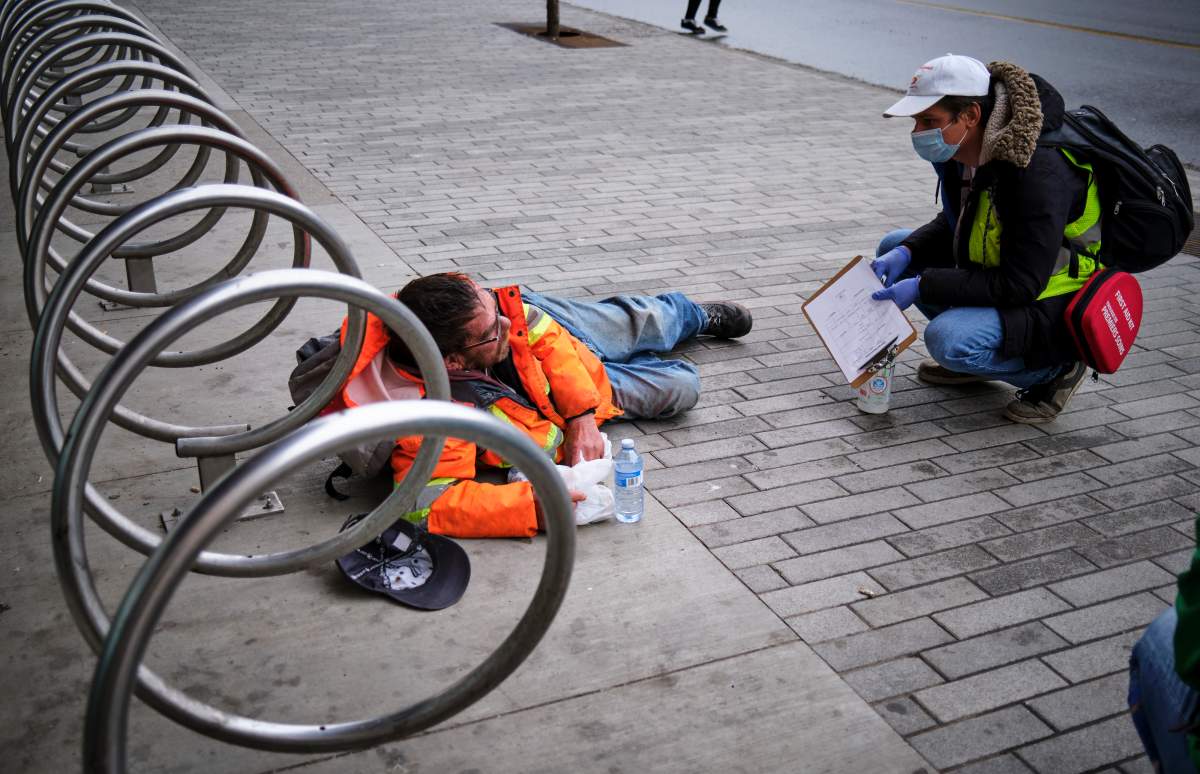 Volunteer Chaz Smith (right) distributes aid to a homeless man in Calgary on Wednesday, May 20, 2020, amid the COVID-19 pandemic.