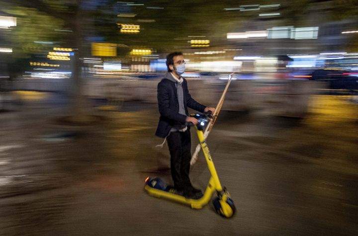 A man wearing a face mask to protect against coronavirus, as he drives his E-scooter in central Frankfurt, Germany, Monday, Oct. 5, 2020. 