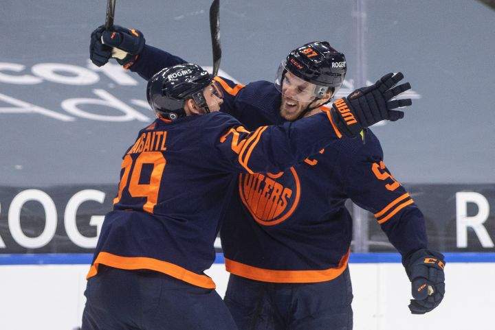 Edmonton Oilers’ Connor McDavid (97) celebrates his 100th point this season with Leon Draisaitl (29) against the Vancouver Canucks during second period NHL action in Edmonton on Saturday, May 8, 2021.