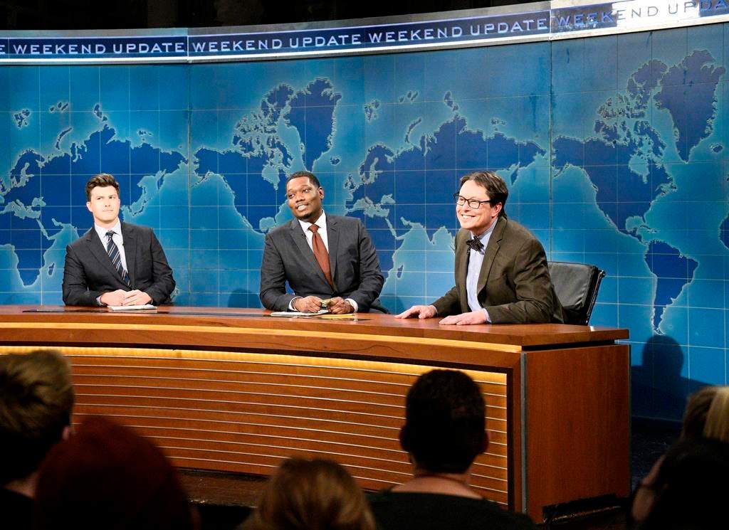 This image released by NBC shows, from left, Colin Jost, Michael Che, and host Elon Musk as financial expert Lloyd Ostertag during the "Weekend Update" sketch on "Saturday Night Live," in New York on May 8, 2021. (Will Heath/NBC via AP).