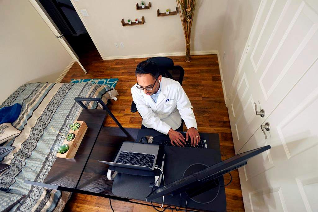 Medical director of Doctor on Demand Dr. Vibin Roy types notes as he listens to a patient during an online primary care visit from his home.
