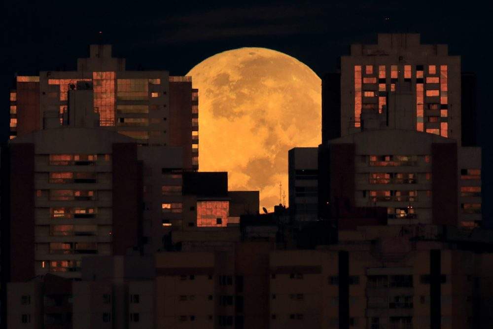 The moon is partially covered by buildings in Brasilia, Brazil, at the start of a total lunar eclipse early Wednesday, May 26, 2021.