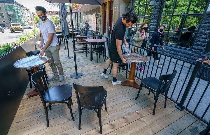 Vincent Aucoin, left, and Victor Obinot set up the patio at the Roseline Cafe in Montreal, on Thursday, May 27, 2021. Restaurant patios are set to open across Quebec on Friday. 
