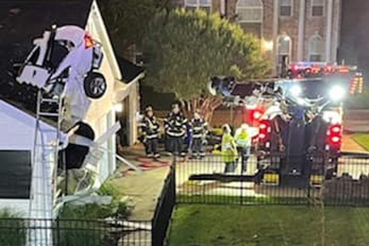 Crews work to remove a car from the roof of a home in Eureka, Missouri, on May 23, 2021.