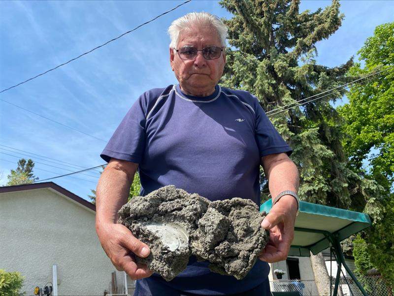 George Monroe holds up a clump of the now hardened cement he scooped out of his Semple Avenue basement.