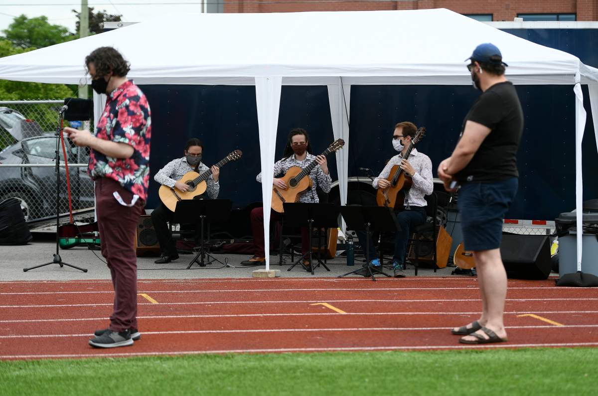 People waiting in line for their vaccines listen to the Ottawa Guitar Trio perform at an outdoor, pop-up COVID-19 vaccination clinic nicknamed "Jabapalooza" on the soccer field at Immaculata High School in Ottawa, on Saturday, June 5, 2021. The city has launched a waitlist tool for residents to scoop up unclaimed vaccine doses.