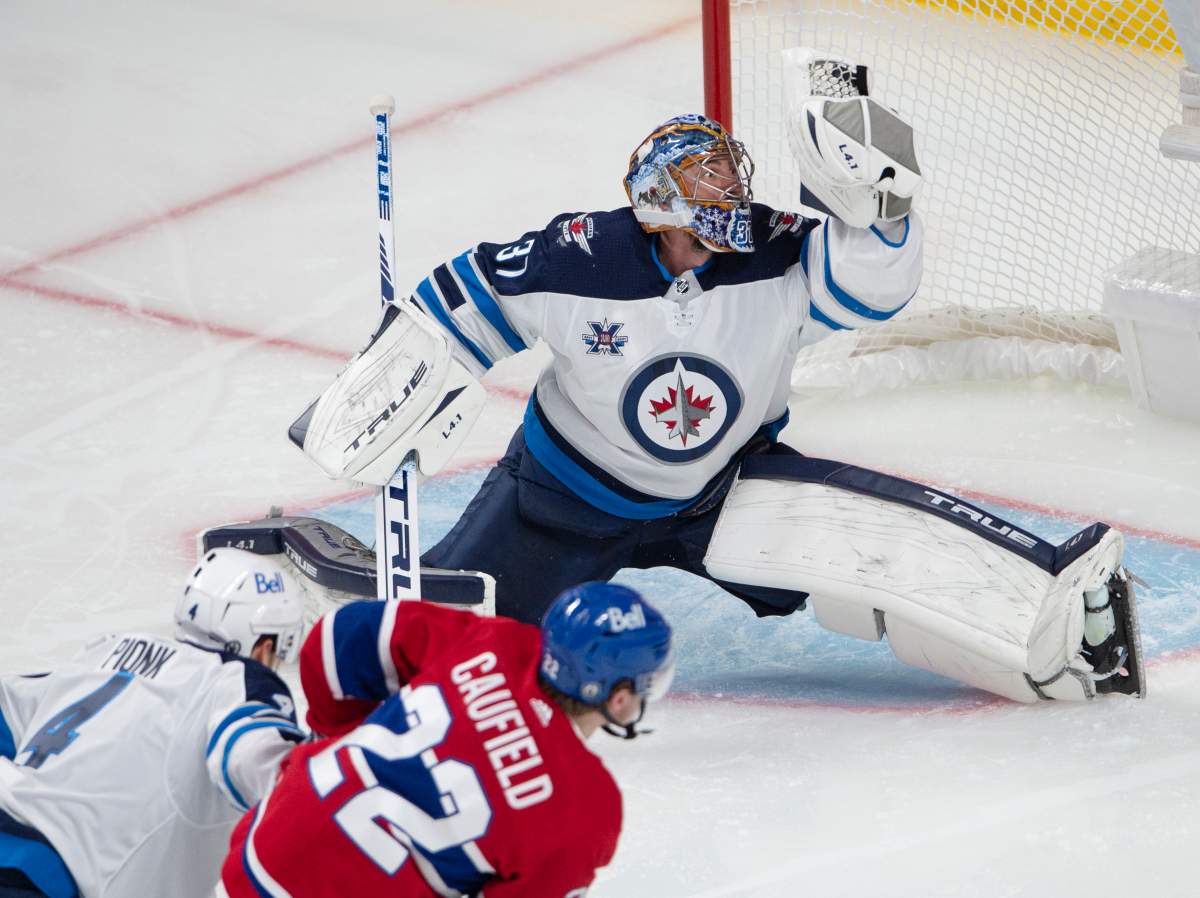 Winnipeg Jets goaltender Connor Hellebuyck (37) makes a glove save on Montreal Canadiens’ Cole Caufield during second period NHL Stanley Cup playoff hockey action in Montreal, Sunday, June 6, 2021.