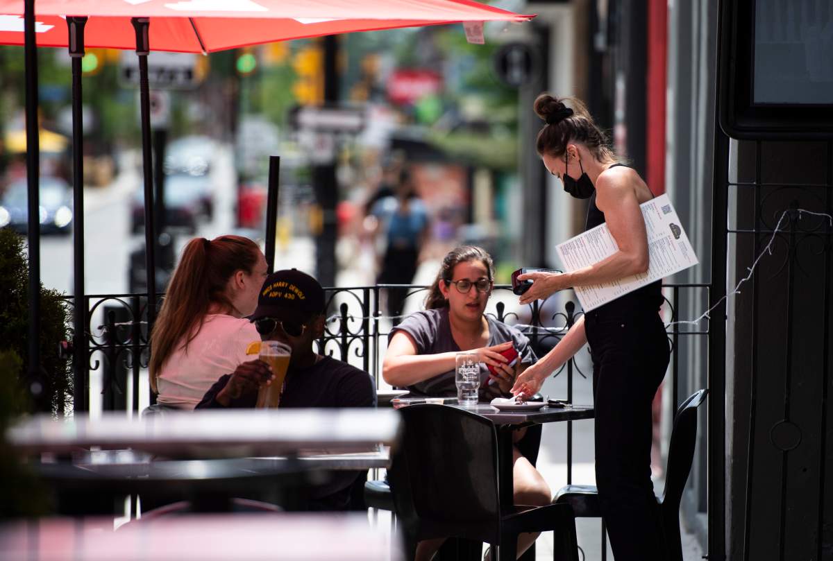 Patrons settle up with a server on a pub's outdoor patio in Ottawa on the first day of Ontario's first phase of reopening amidst the third wave of the COVID-19 pandemic, on Friday, June 11, 2021.
