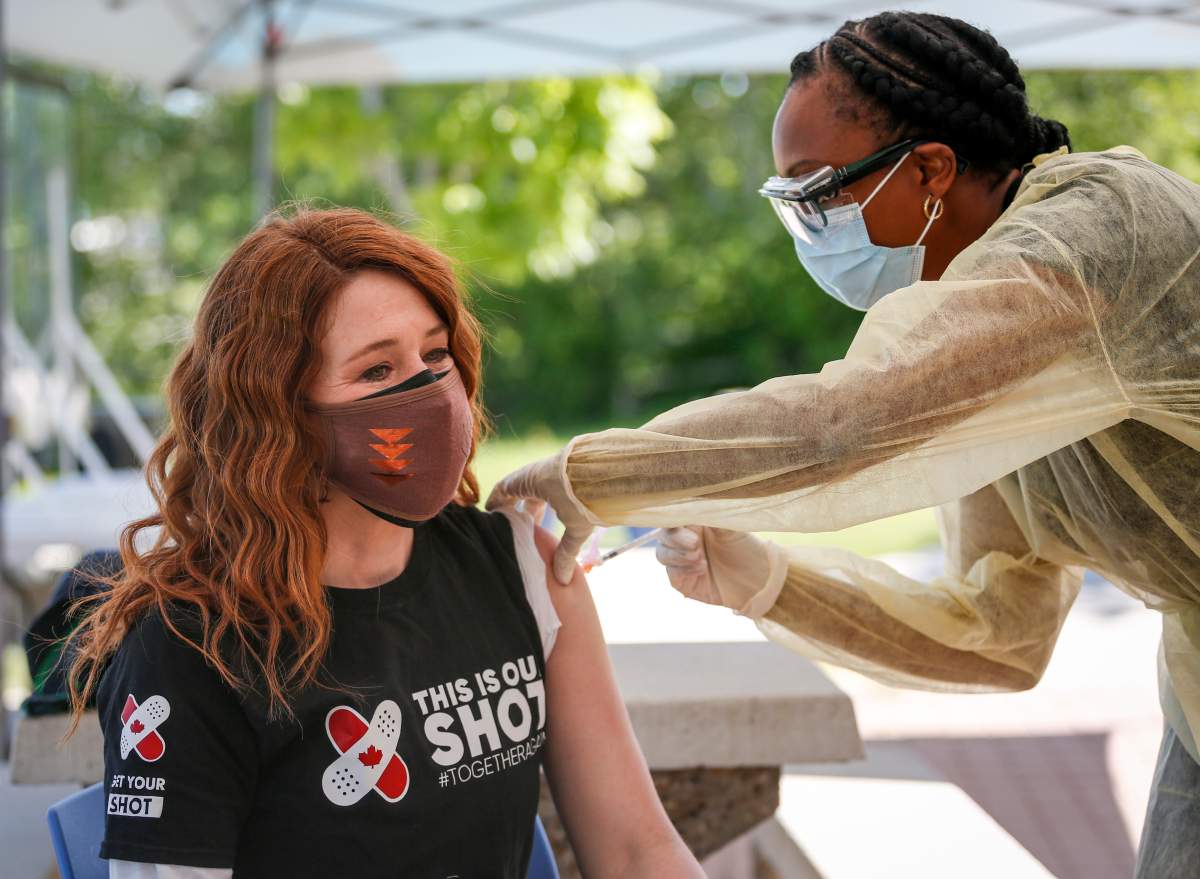 Olympic medalist Clara Hughes, left, receives a second dose of COVID-19 vaccine at a community vaccination clinic at the Stoney Nakoda First Nation health services centre in Morley, Alta., Thursday, June 17, 2021.