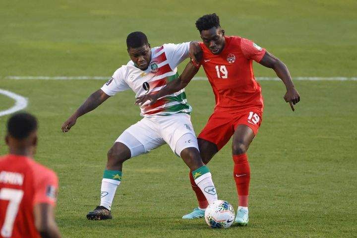 Canada’s Alphonso Davies (19) and Suriname’s Nigel Hasselbaink (9) work for the ball during the first half of a World Cup 2022 Group B qualifying soccer match Tuesday, June 8, 2021, in Bridgeview, Ill.