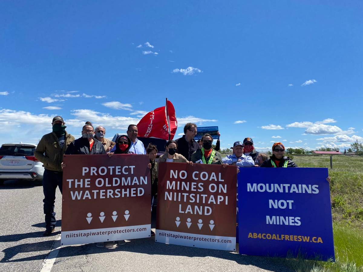 MLA Shannon Phillips, MLA Marlin Schmidt, Corb Lund, and a group of anti-coal mining protestors stand on the side of Highway 3.