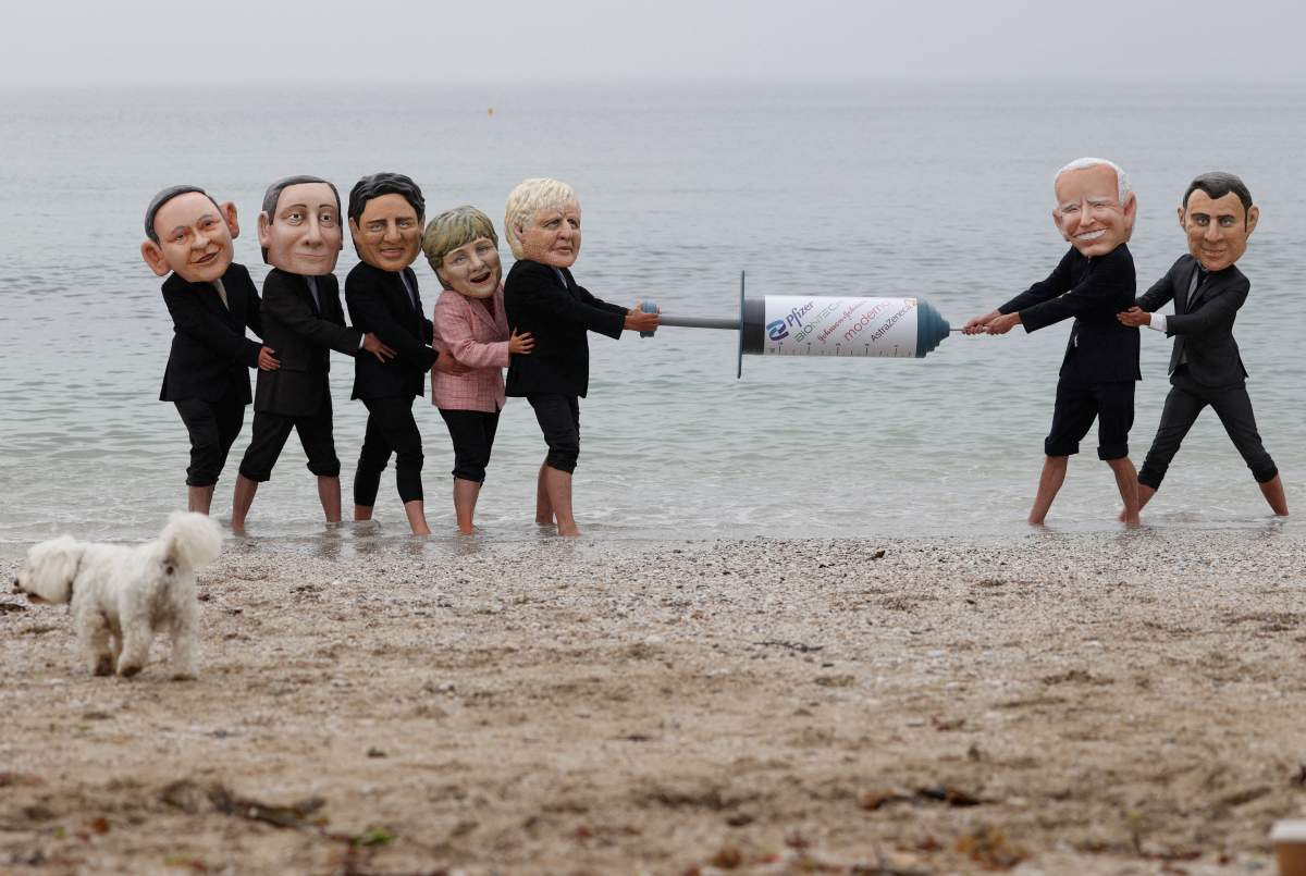 Activists wearing giant heads of the G7 leaders tussle over a COVID-19 vaccine syringe during an action by charity Oxfam to highlight intellectual property for vaccines on Swanpool beach in Falmouth, Cornwall on the sidelines of the G7 summit on June 11, 2021.