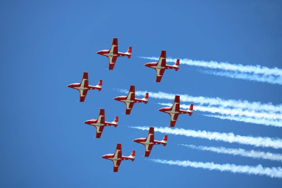 Eight snowbird planes fly in formation across a clear blue sky.