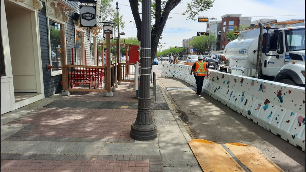 Crews install barriers to allow for extended sidewalks along Edmonton’s Whyte Avenue on June 2, 2021.