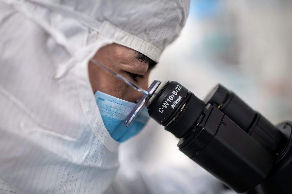 In this picture taken on April 29, 2020, an engineer looks through a microscope at a facility in China.
