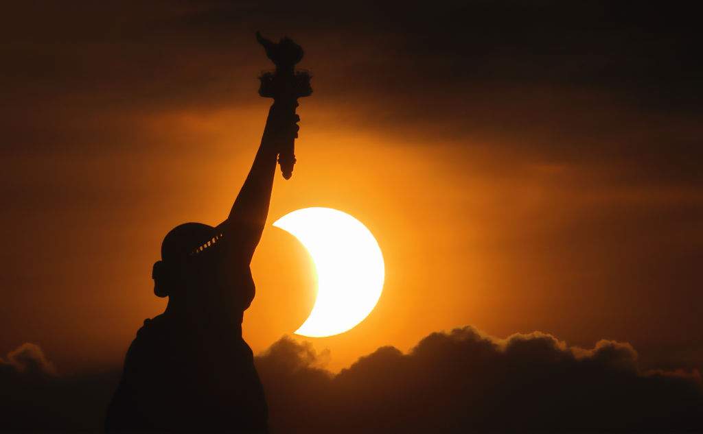The sun rises next to the Statue of Liberty during an annular eclipse on June 10, 2021, in New York City.