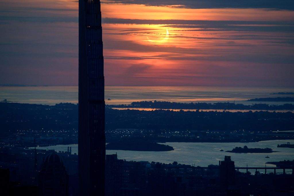 A partial solar eclipse rises between buildings of the Manhattan skyline from the Edge viewing deck in New York on June 10, 2021.