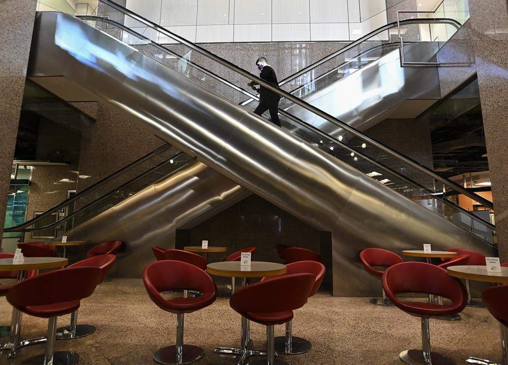 A man rides an escalator from the underground PATH at the lunch hour on Oct. 13, 2020.