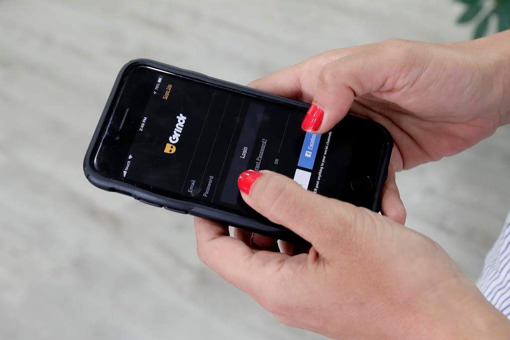 FILE - In this Wednesday, May 29, 2019 file photo, a woman looks at the Grindr app.