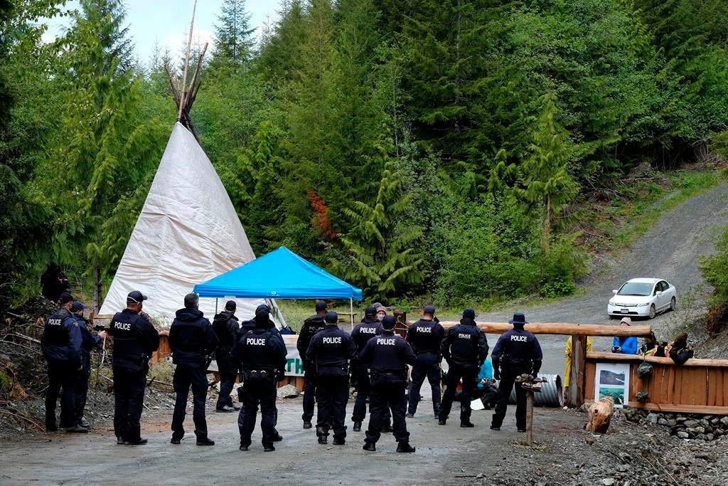 RCMP officers approach an anti-logging blockade in Caycuse, B.C. on Tuesday, May 18, 2021. THE CANADIAN PRESS/Jen Osborne.