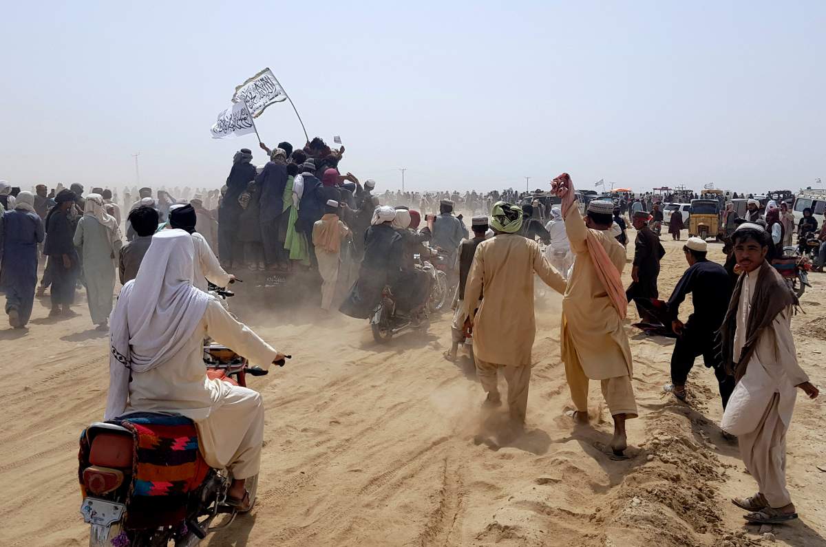 Supporters of the Taliban carry the Taliban’s signature white flags in the Afghan-Pakistan border town of Chaman, Pakistan, Wednesday, July 14, 2021. The Taliban are pressing on with their surge in Afghanistan. (AP Photo/Tariq Achkzai)