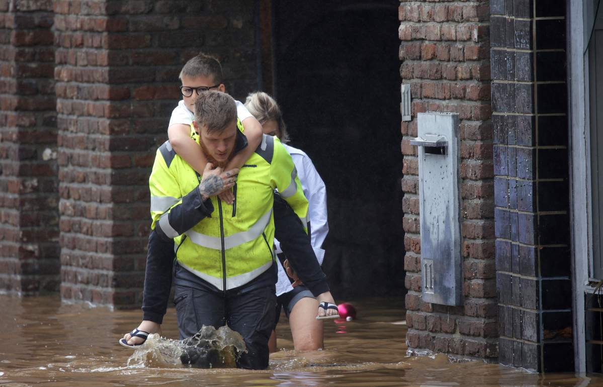 A rescue worker helps residents evacuate as floodwaters run down a main street in Pepinster, Belgium, Thursday, July 15, 2021.