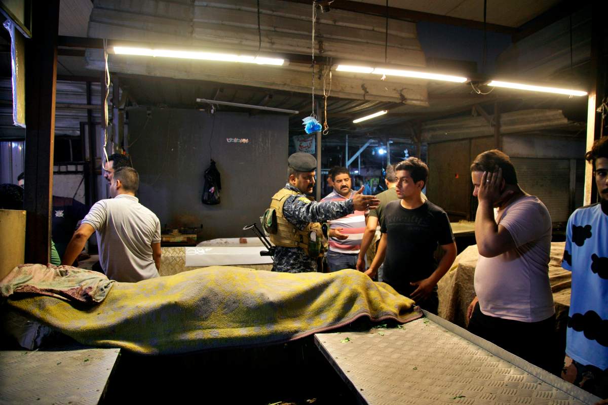 People and security forces gather at the site of a bombing in Wahailat market in Sadr City, Iraq, July. 19, 2021.