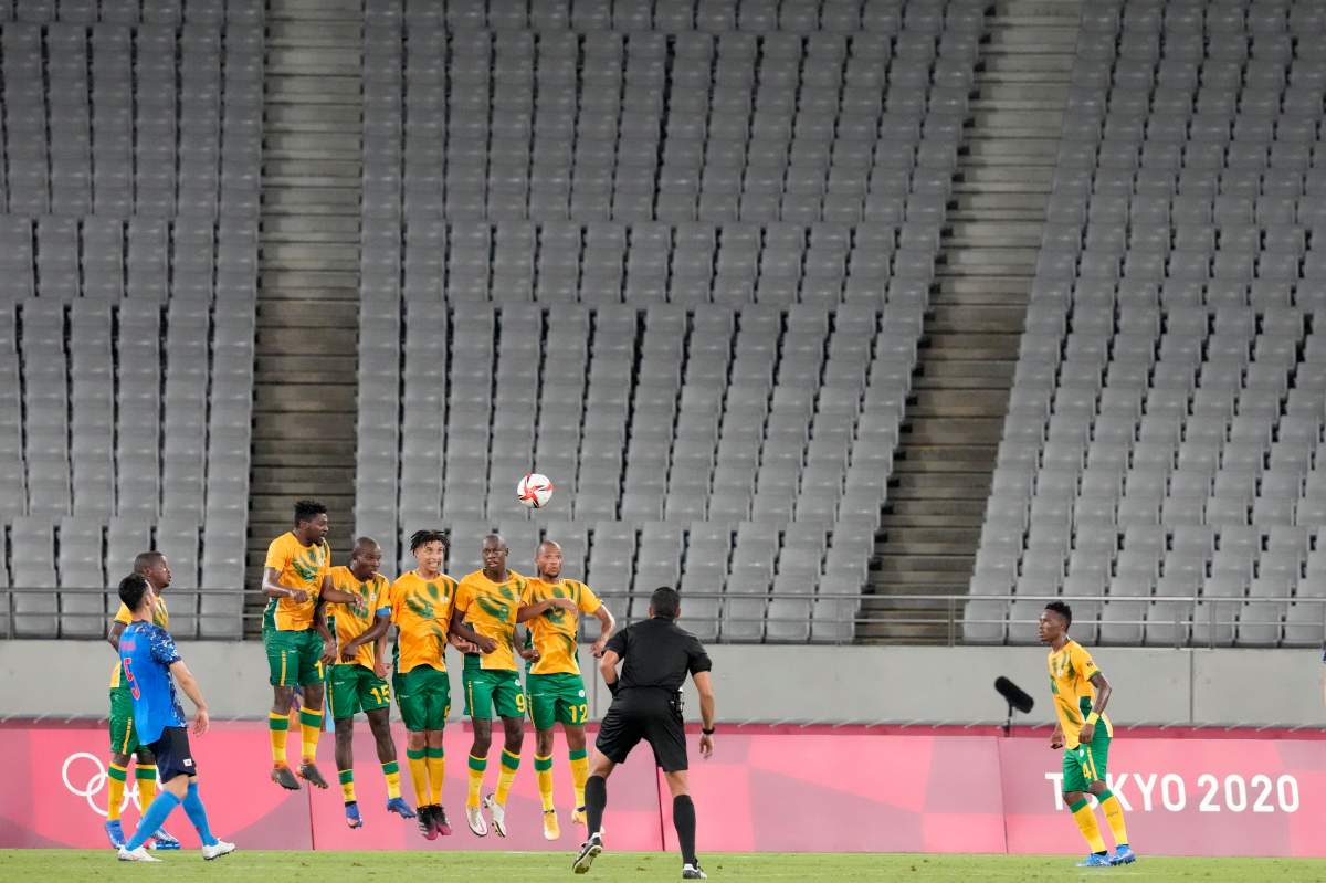 Japan’s Maya Yoshida, left, takes a penalty kick against South Africa as the stands sit empty during a men’s soccer match at the 2020 Summer Olympics, July 22, 2021, in Tokyo, Japan.