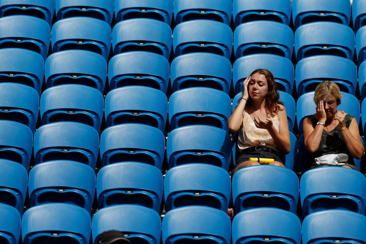 Fans apply sunscreen as they wait for a match in their third round match between Argentina's Diego Schwartzman and Serbia's Dusan Lajovic at the Australian Open tennis championship in Melbourne, Australia, Friday, Jan. 24, 2020.